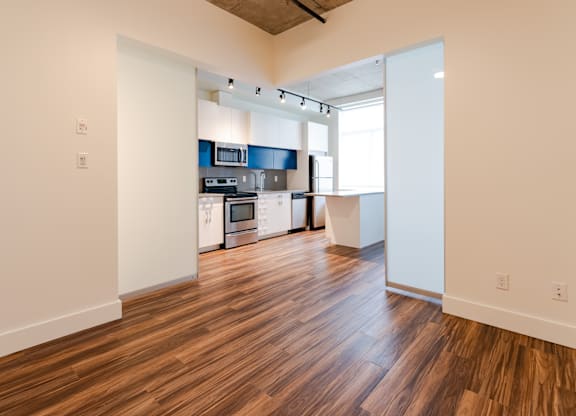 A kitchen with white cabinets and a wooden floor.