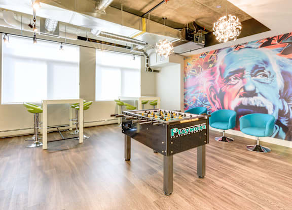 A foosball table is in the middle of a room with a bar and chairs.