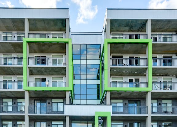 A modern building with balconies and a large glass window in the center.
