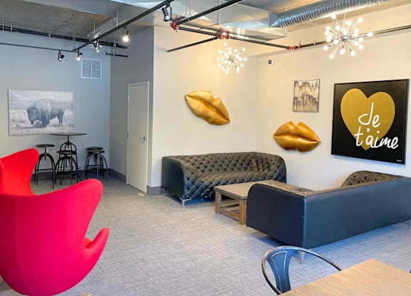 A modern office space with a red chair, a black sofa, and a wall with a heart-shaped sign that says "Je t'aime".