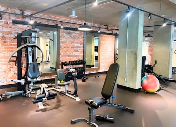 A gym with a variety of equipment including a weight bench, a leg press machine, and a medicine ball.