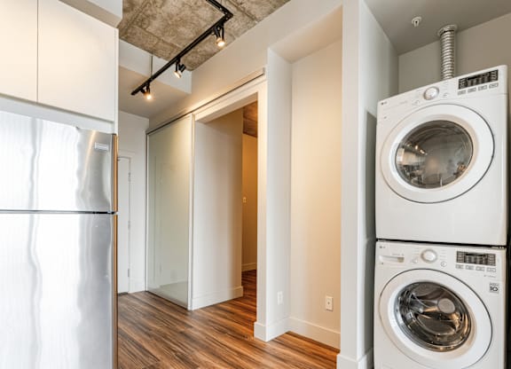A white washing machine sits in a room with a wooden floor.