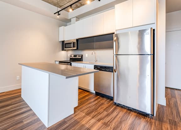 A kitchen with a refrigerator, microwave, and oven.