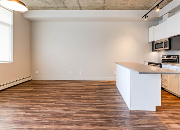 A kitchen with a white counter and wooden floors.