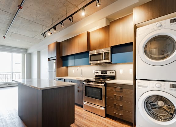A modern kitchen with a washing machine and dryer built into the cabinetry.