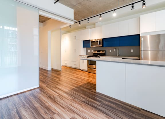 A kitchen with white cabinets and a blue accent wall.