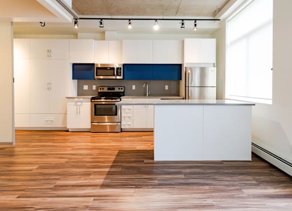 A modern kitchen with white and blue cabinets and stainless steel appliances.