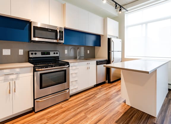 A modern kitchen with a stove, oven, microwave, and refrigerator.