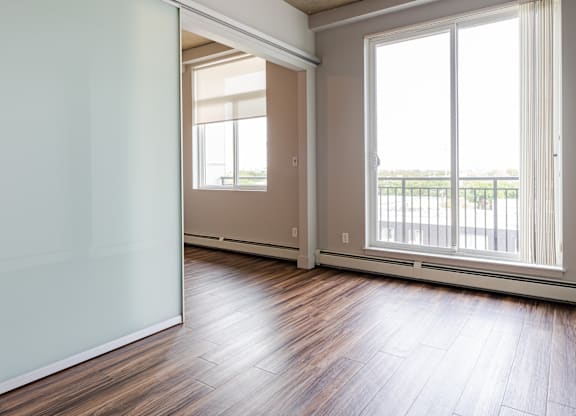 A room with a sliding glass door and wooden flooring.