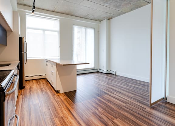 A kitchen with a refrigerator, sink, and wooden floors.