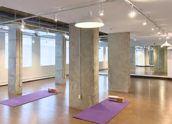 A yoga studio with purple mats and concrete pillars.