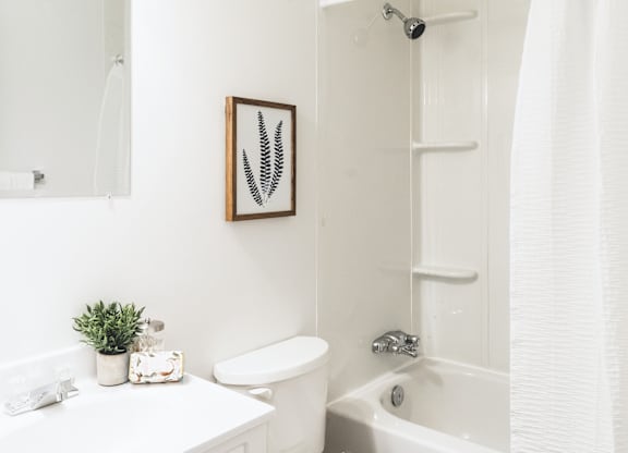 A white bathroom with a toilet, sink, and bathtub.