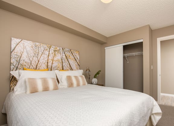 A bedroom with a large bed and a painting on the wall.