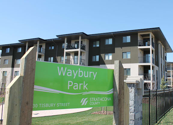 A green sign that says Waybury Park in front of a building.