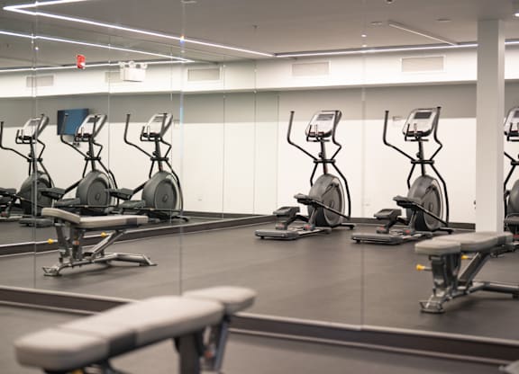 A gym with exercise bikes and a bench.
