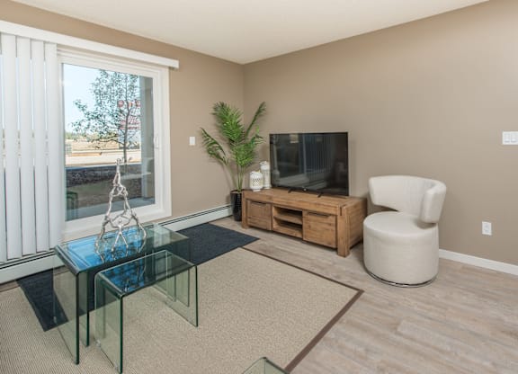 A living room with a glass coffee table and a white chair.