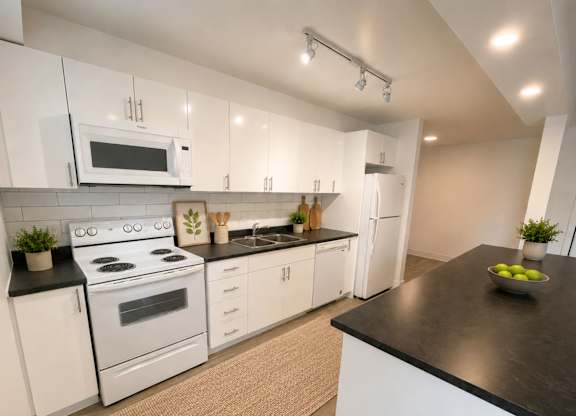 A modern kitchen with white cabinets and black countertops.