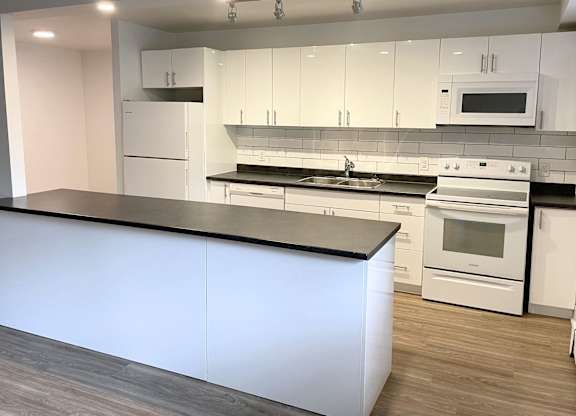 A modern kitchen with white cabinets and a black countertop.