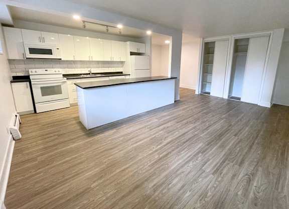 A kitchen with a white countertop and wooden flooring.