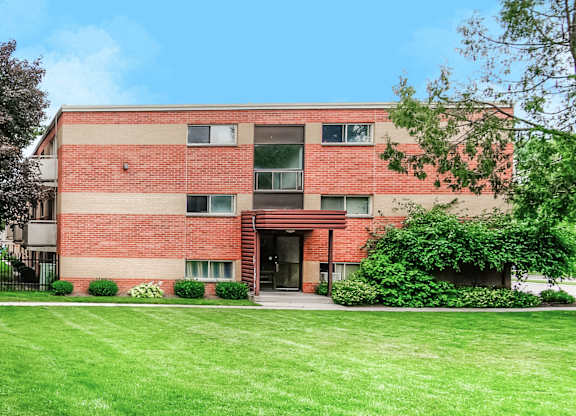 A red brick building with a green lawn in front.