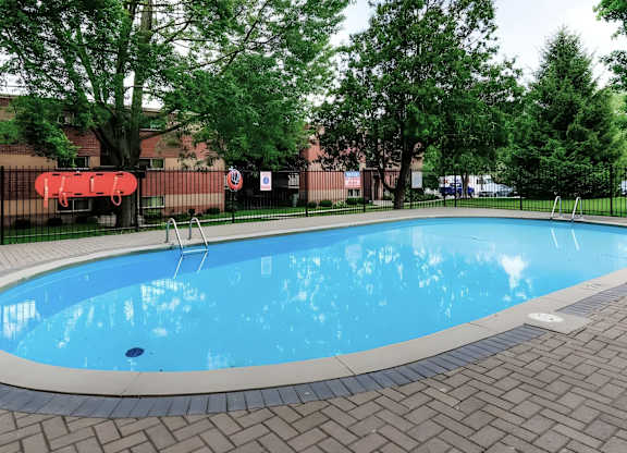 A small pool surrounded by trees and a black fence.