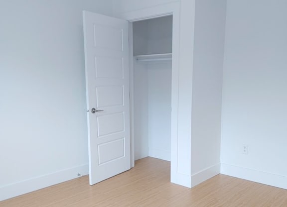 A white door is open to a room with a wooden floor.