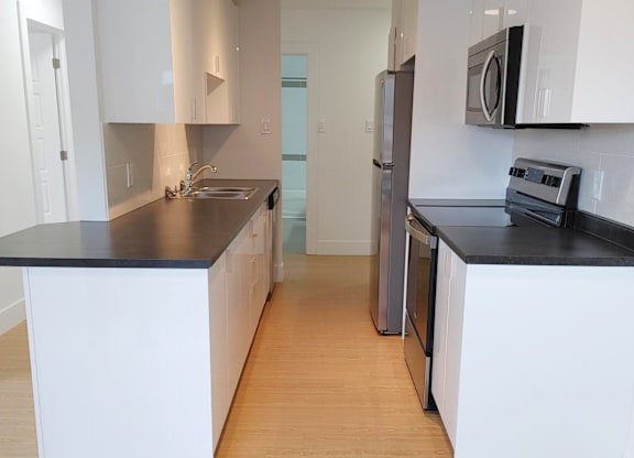 A kitchen with white cabinets and black countertops.