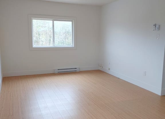 A room with a window and wooden flooring.