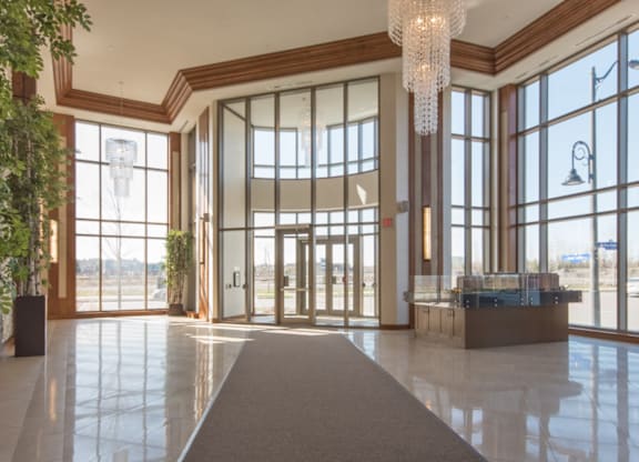A large, well-lit lobby with a long carpet leading to a set of double doors.