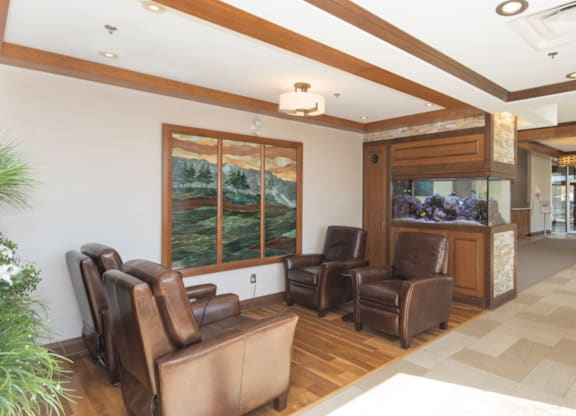 A living room with brown leather chairs and a large window.
