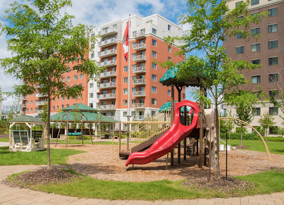 A playground with a red slide and a green canopy.