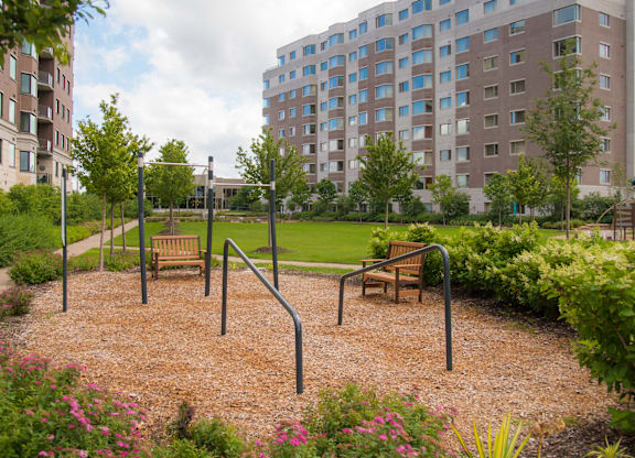A playground with a swing set and a slide in front of a large apartment building.