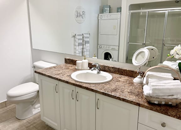 A bathroom with a toilet, sink, and mirror.