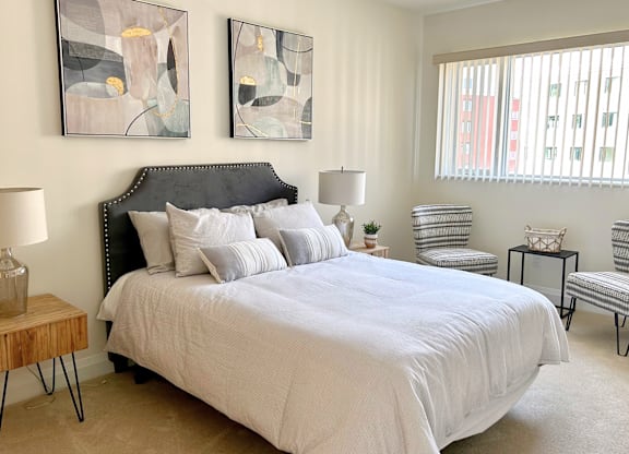 A bedroom with a large bed and two abstract paintings on the wall.