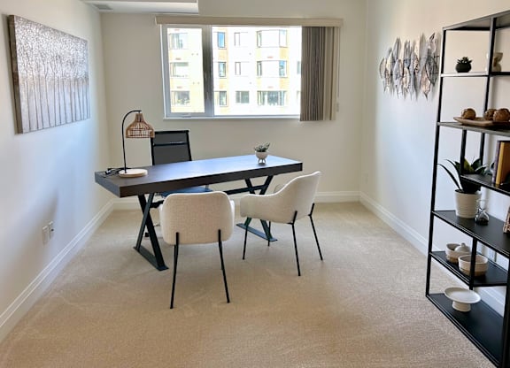 A black dining table with four chairs in a room with a window.