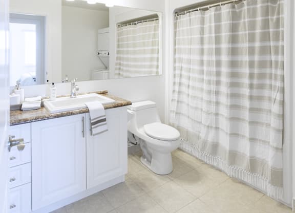 A white bathroom with a toilet, sink, and shower curtain.