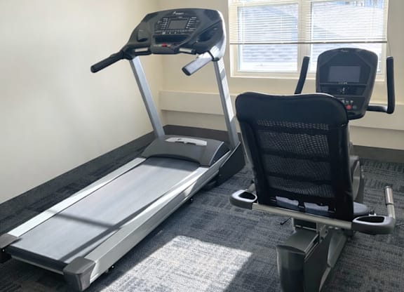 A treadmill and a stationary bike are in a room.