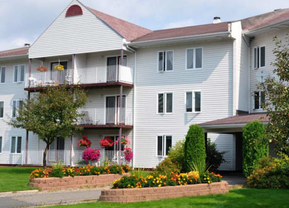 A white building with a red roof and a balcony with flowers.