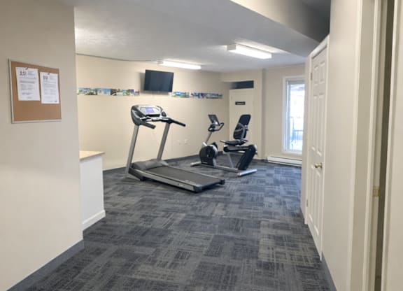 A gym room with a treadmill and a stationary bike.
