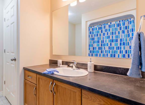 A bathroom with a sink, mirror, and blue towel.
