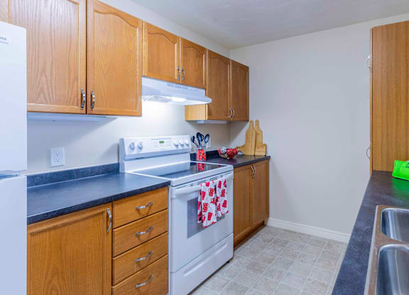 A kitchen with wooden cabinets and a white stove top oven.