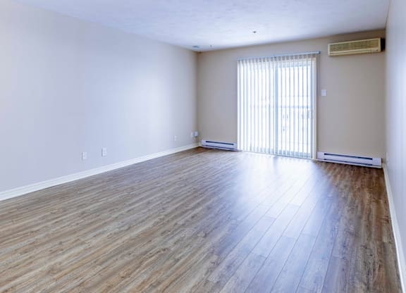 A room with wooden flooring and a window with blinds.