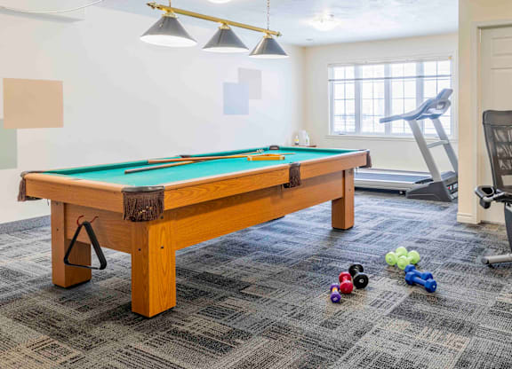 A pool table with a green felt cloth and a set of pool balls on the floor.