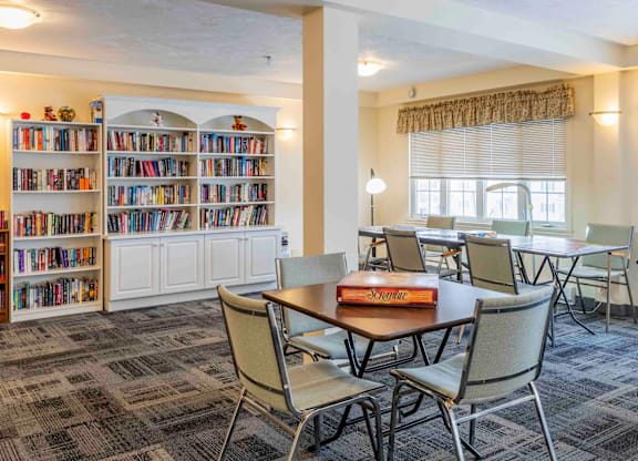 A room with a table, chairs, and a bookshelf filled with books.