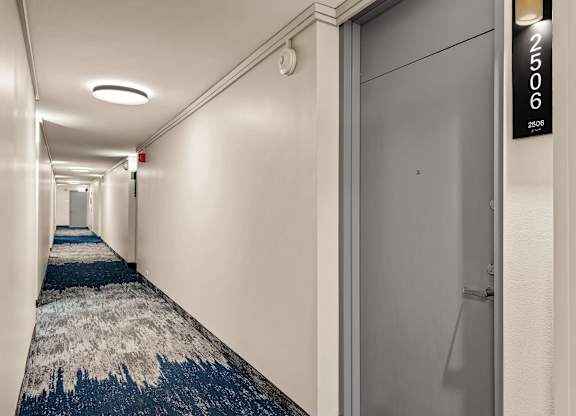 A hallway with a blue carpet and white walls.