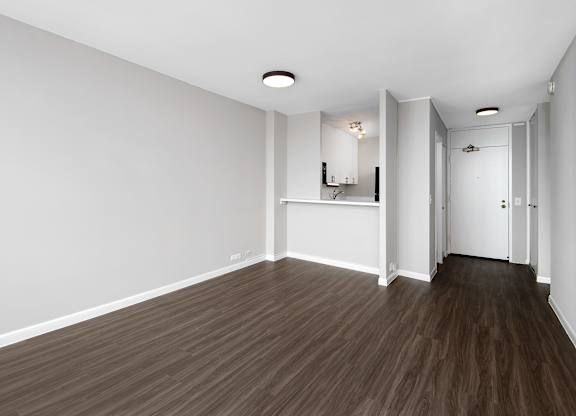 A room with wooden flooring and white walls.