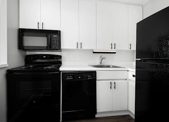 A black and white photo of a kitchen with white cabinets.