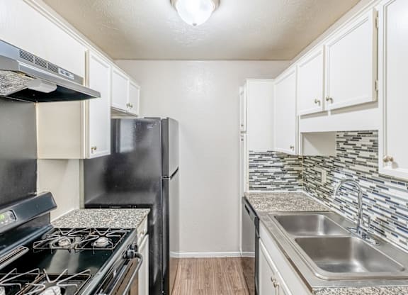 A kitchen with black and white appliances and a tiled backsplash.