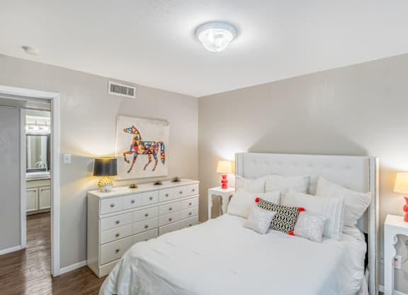 A bedroom with a large bed, a dresser, and a painting on the wall.