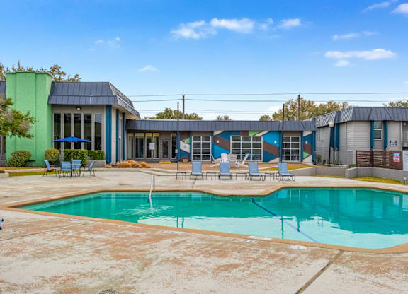 A swimming pool in front of a building with blue and green walls.